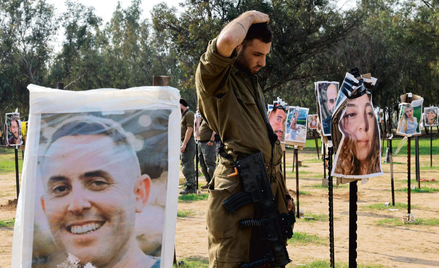 Izraelski żołnierz w miejscu, w którym odbywał się festiwal Supernova, wśród zdjęć ofiar ataku z 7 p