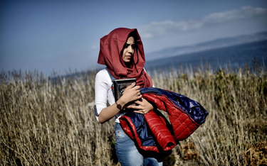 Kobieta idąca przez pole po przybyciu uchodźców i imigrantów na grecką wyspę Lesbos