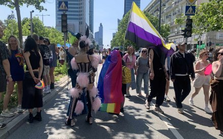 Jedna z osób ma na sobie ekstrawagancki strój z różowymi piórami