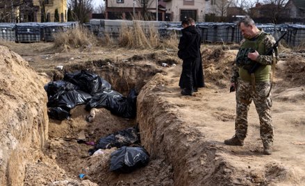 Żołnierze nad masowym grobem w Buczy