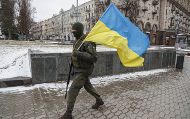 Ukraiński żołnierz z flagą Ukrainy na ulicach Kijowa