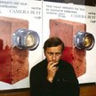Jerzy Stuhr, odtwórca roli Filipa Mosza, na tle plakatu autorstwa Andrzeja Pągowskiego do filmu „Ama
