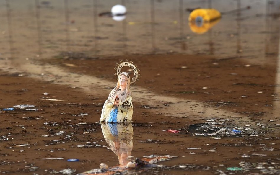 Figurka Matki Bożej z Lourdes pływająca wśród odpadów na zalanej ulicy w Mandelieu-la-Napoule w połu