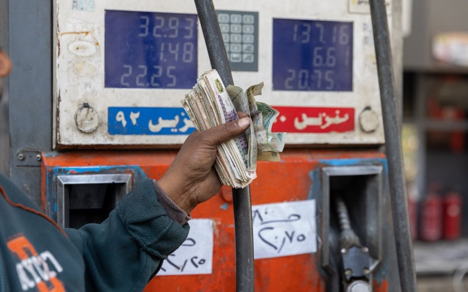 Pracownik stacji benzynowej obsługiwanej przez CPC-Egypt w Kairze z garścią banknotów w funtów egips