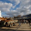 Ludzie mijają uszkodzony wagon kolejowy i zniszczone rosyjskie maszyny wojskowe wystawione w pobliżu