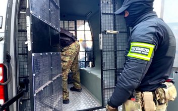 Funkcjonariusze wprowadzają cudzoziemców do pojazdu służbowego