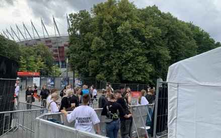 Rozległy namiot ze stoiskami sprzedającymi oficjalne gadżety koncertowe