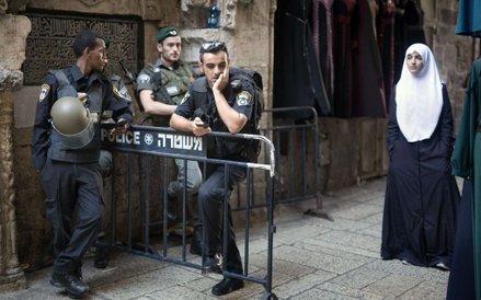 Palestyńska kobieta przechodząca obok punktu kontrolnego izraelskiej policji na starym mieście w Jer