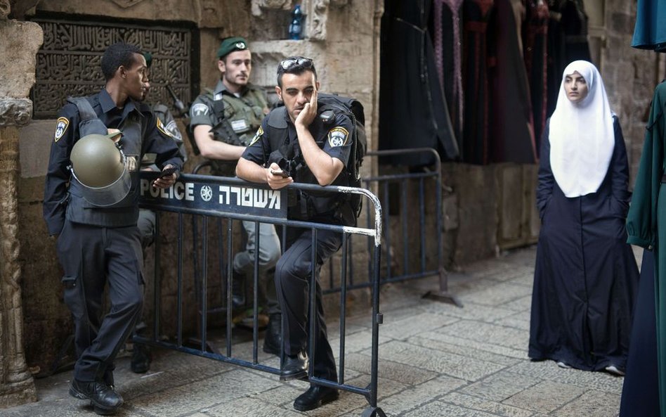 Palestyńska kobieta przechodząca obok punktu kontrolnego izraelskiej policji na starym mieście w Jer