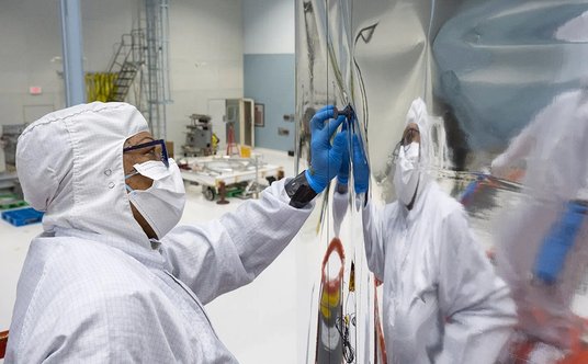 Technik Brenda Estavia instaluje najgłębszą warstwę osłony przeciwsłonecznej na konstrukcji osłony a