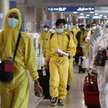 Pasażerowie na lotnisku w Seulu, w odzieży ochronnej
