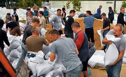 W Dobrzykowie strażacy, żołnierze i mieszkańcy budowali wał, który ma zapobiec dalszym zalaniom i za