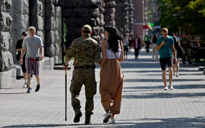 Ranny ukraiński żołnierz spaceruje z kobietą w centrum Kijowa, 14 sierpnia 2023 r