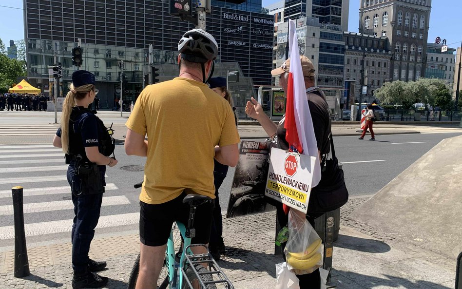 Scena na ulicy podczas Parady Równości. W tle widać patrole policji, które zabezpieczają wydarzenie,