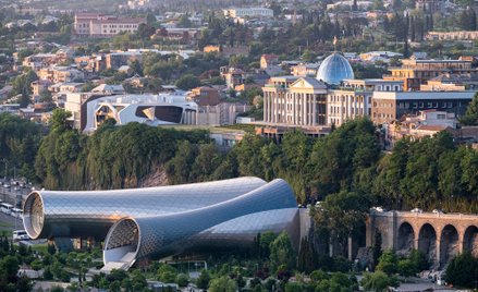 Awangardowa forma gmachu mocno kontrastuje z historycznymi budynkami Tbilisi.