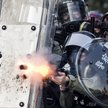Przyparta przez demonstrantów do muru policja strzela pociskami gazowymi