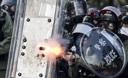 Przyparta przez demonstrantów do muru policja strzela pociskami gazowymi