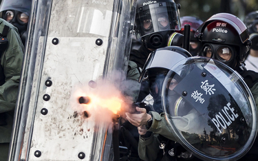 Przyparta przez demonstrantów do muru policja strzela pociskami gazowymi