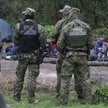 Grupa uchodźców i straż graniczna w pobliżu miejscowości Usnarz Górny k. Krynek, sierpień 2021 r.