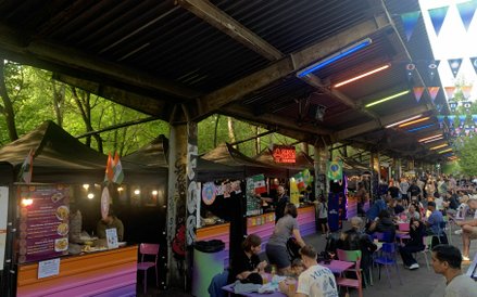 Długi korytarz Nocnego Marketu na dawnych peronach, ożywiony przez neony, chorągiewki i różnorodne s