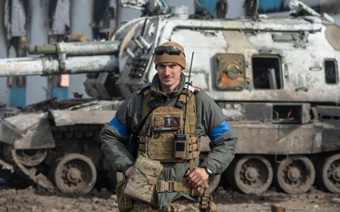 Ukraiński żołnierz przed zniszczonym rosyjskim działem samobieżnym
