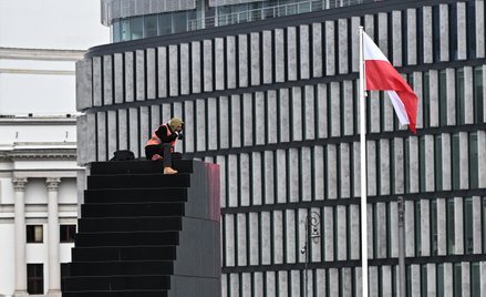 Aktywista Ostatniego Pokolenia na Pomniku Ofiar Tragedii Smoleńskiej 2010 roku na pl. Piłsudskiego w