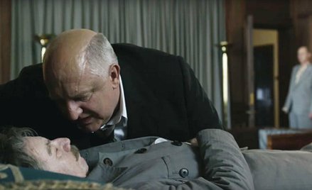 Ławrentij Beria (Simon Russell Beale) pochyla się nad martwym wodzem (Gary Oldman) – scena z filmu.