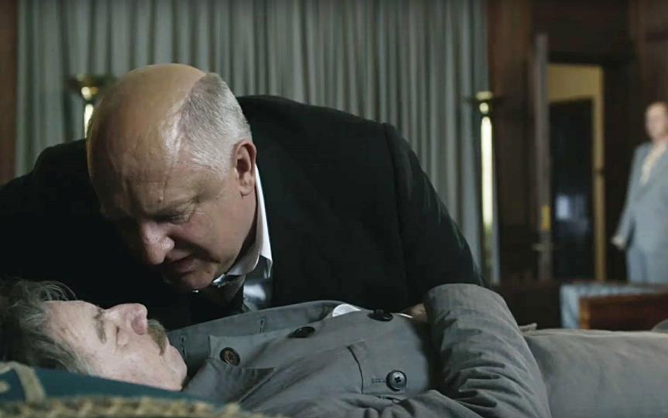 Ławrentij Beria (Simon Russell Beale) pochyla się nad martwym wodzem (Gary Oldman) – scena z filmu.
