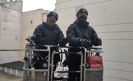 Policjanci w koszu strażackiego wysięgnika podczas rozmowy z członkami Lotnej Brygady Opozycji