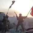 Członkowie Grupy Wagnera machający rosyjską flagą narodową i flagą Grupy Wagner na dachu zniszczoneg