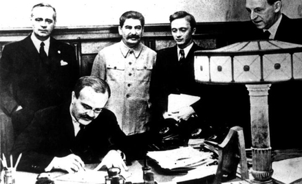 Wiaczesław Mołotow podpisuje pakt z Niemcami. Za nim po prawej stoi Józef Stalin, a po lewej Joachim