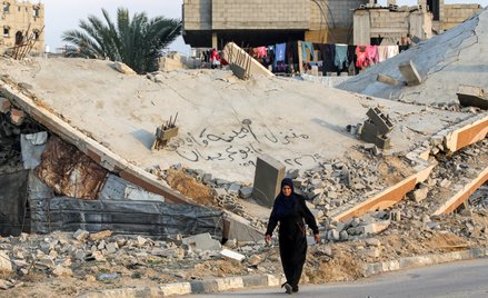 Kobieta przechodząca obok zrujnowanego budynku w obozie al-Buradż w środkowej części Strefy Gazy