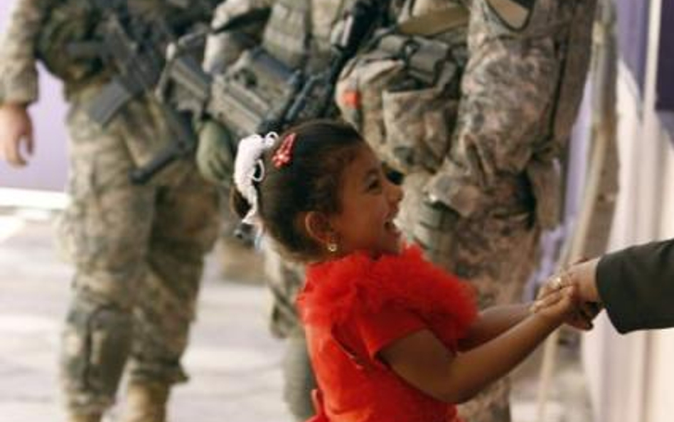 Irak, Bagdad. Dziewczynka bawiąca się w pobliżu amerykańskich żołnierzy
