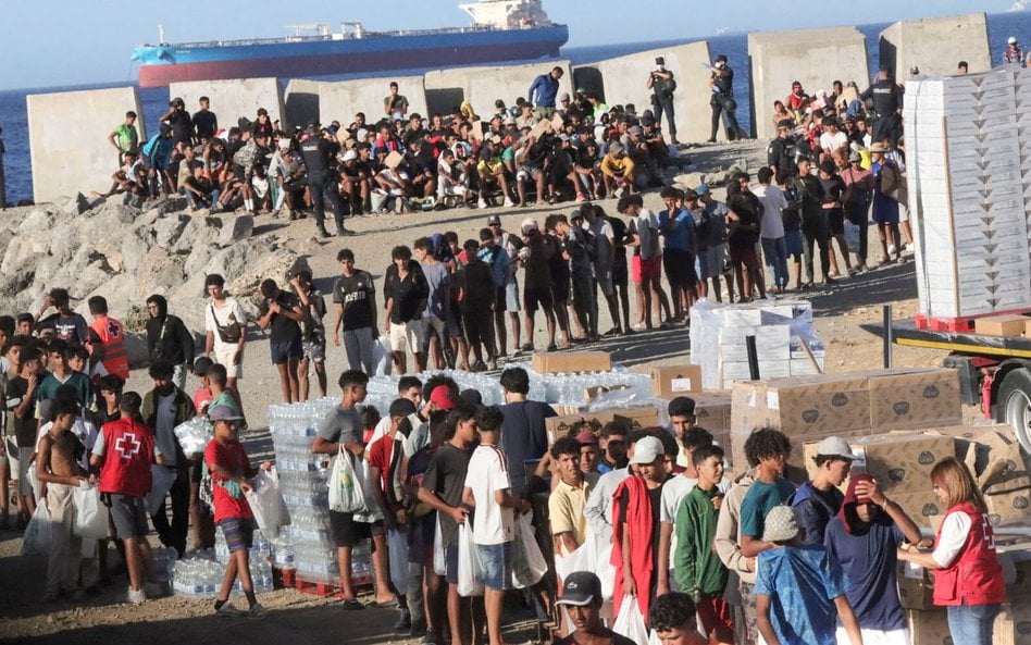 Członkowie Czerwonego Krzyża rozdają żywność migrantom na plaży El Trampolín w Ceucie.