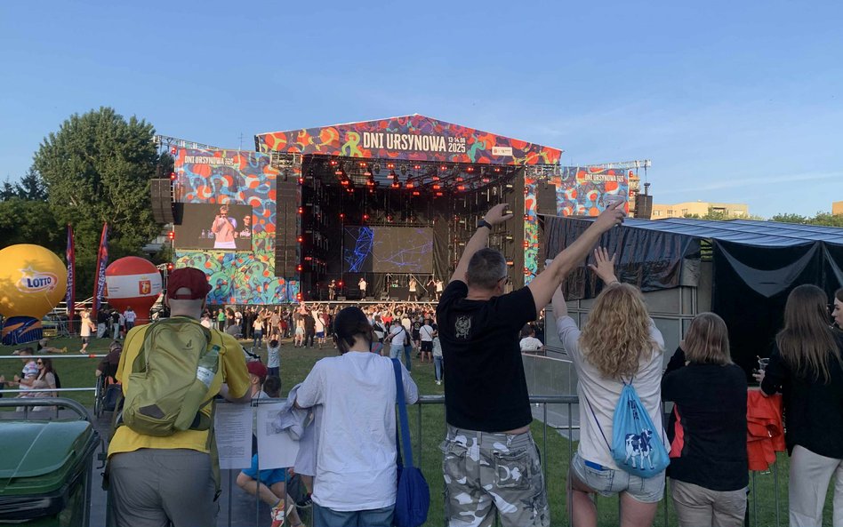 Grupa osób z zapałem podziwiająca koncert z dalszej perspektywy