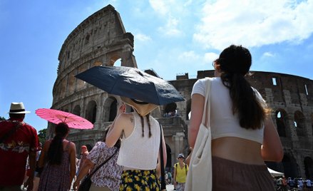 Turyści chronią się przed słońcem przed rzymskim Koloseum