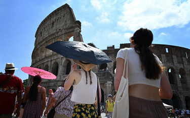 Turyści chronią się przed słońcem przed rzymskim Koloseum