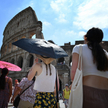Turyści chronią się przed słońcem przed rzymskim Koloseum