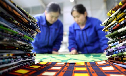 Pracownik produkuje tkaninę woskową na eksport do Afryki w warsztacie produkcji tekstyliów w mieście