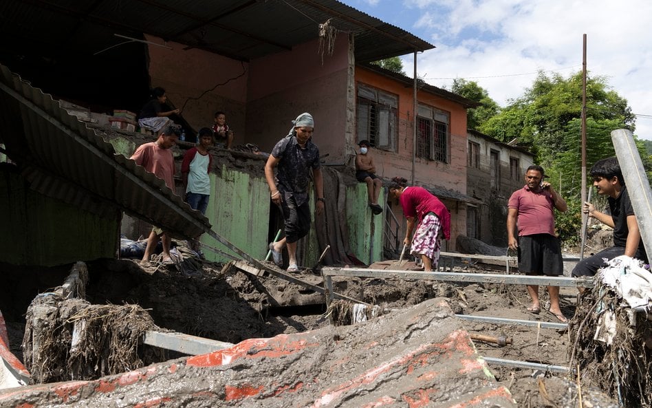 Ludzie sprzątają swój zniszczony dom po powodzi błyskawicznej w dystrykcie Dhading w Nepalu.