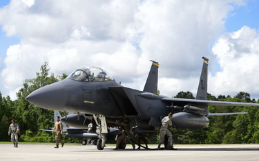Lotnicy różnych specjalności tankują samolot myśliwsko-bombowy F-15E Strike Eagle, którego pilot cał