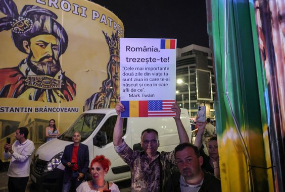 Wybory w Rumunii. Mężczyzna trzyma planszę  z hasłem „Rumunio, obudź się!” oraz cytatem z Marka Twai