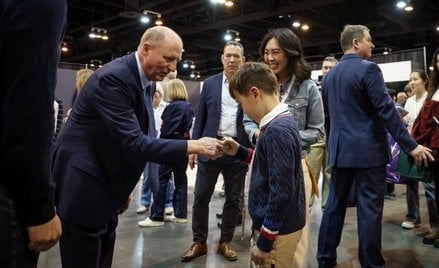 Prezes Berkshire Hathaway, Greg Abel, przybija piątkę, witając akcjonariuszy podczas dorocznego waln
