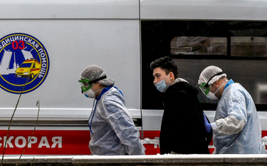 Pracownicy ochrony zdrowia prowadzą chorego na COVID-19 do szpitala
