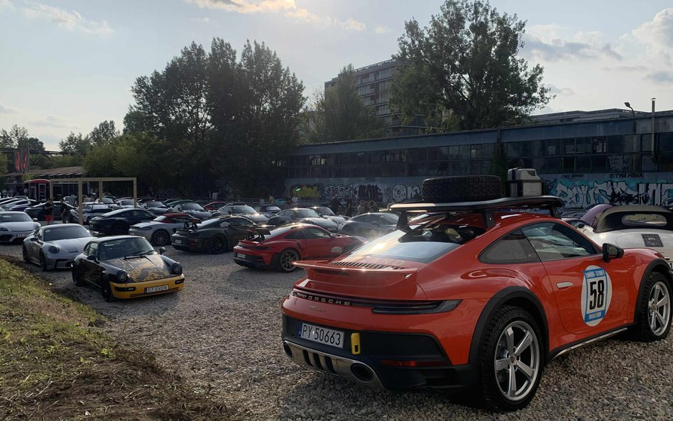 Szeroka panorama parkingu pełnego Porsche, od klasycznych 911 po nowoczesne modele