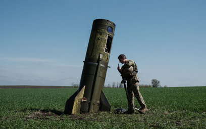 Ukraiński żołnierz ogląda fragment rosyjskiego pocisku balistycznego, który spadł na pole w pobliżu 