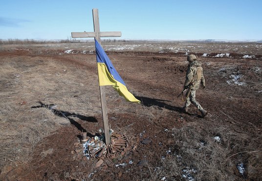 Ukraiński żołnierz przechodzi obok własnoręcznie wykonanego pomnika poległych kolegów – żołnierzy. S