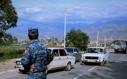 Policjant z Armenii obserwuje pojazdy przewożące uchodźców przybywają do centrum rejestracji w pobli