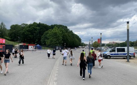 Widok na tereny wokół stadionu, gdzie gromadzą się uczestnicy koncertu, w oddali widoczny radiowóz p