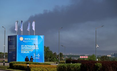 Policjanci stoją przed banerem i flagami z logo Międzynarodowego Forum Ekonomicznego w Petersburgu (
